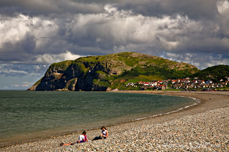 Photo of the Little Orme taken from the East Shore promenade at Llandudno on the North Wales coast with family on the pebble beach