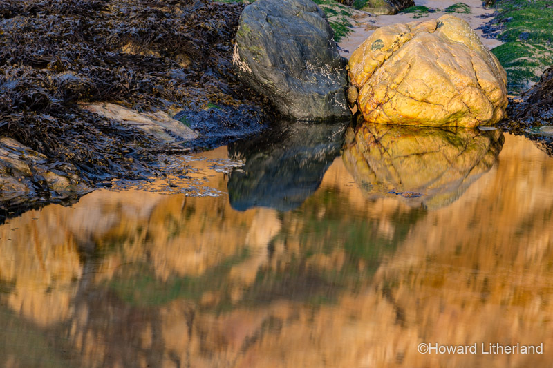 Rocks reflecting in a tidal pool on the beach at Church Bay, Anglesey, North Wales