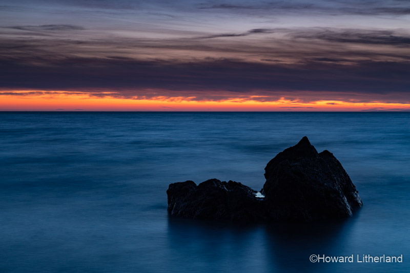 Rock in the sea at dusk at Church Bay, Anglesey, North Wales