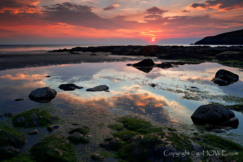 Tidal pool and rocks on the beach at Church Bay, Anglesey, North Wales, at sunset
