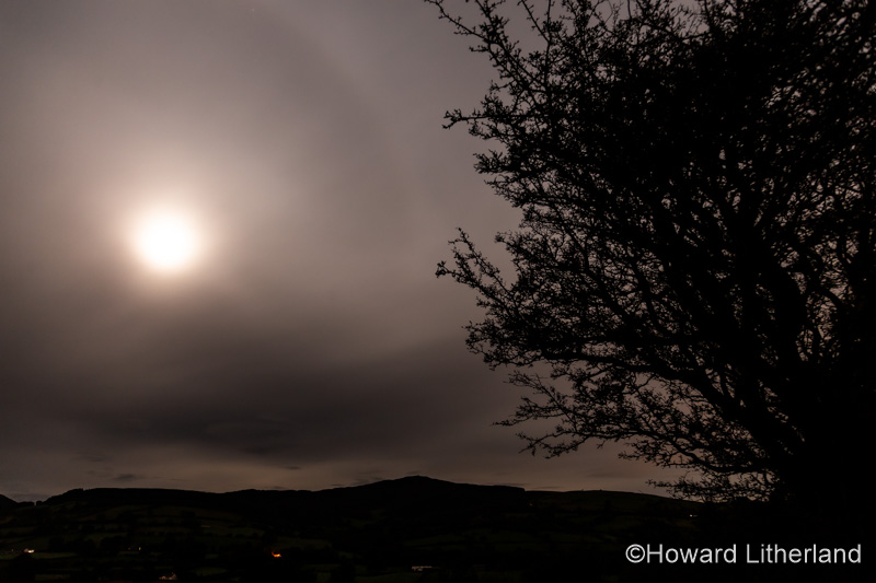 Full moon shining through clouds over the Clwydian Range AONB, North Wales