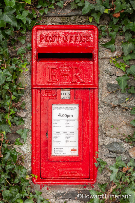 Traditional red UK postbox set in an ivy covered wall