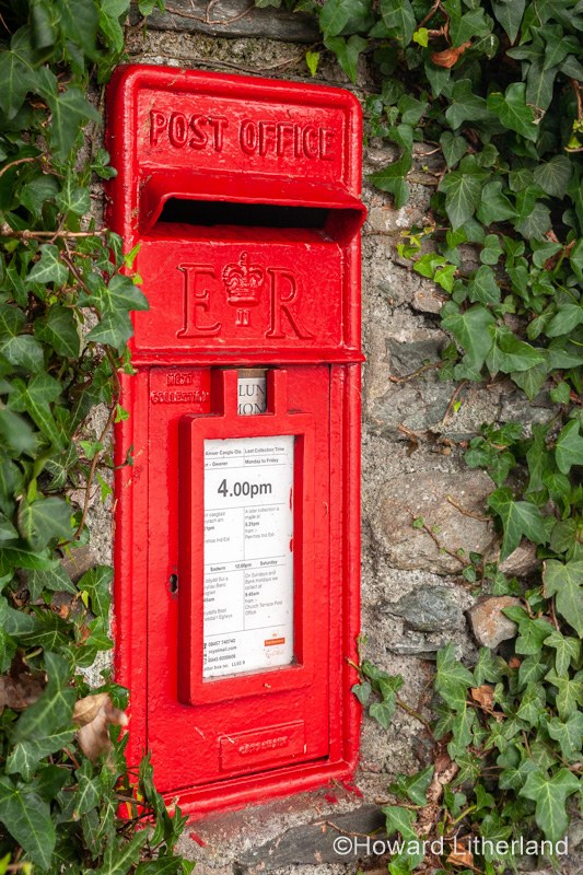 Traditional red UK postbox set in an ivy covered wall