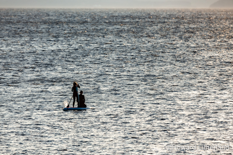Couple paddleboarding off Llanddona beach, Anglesey, North Wales