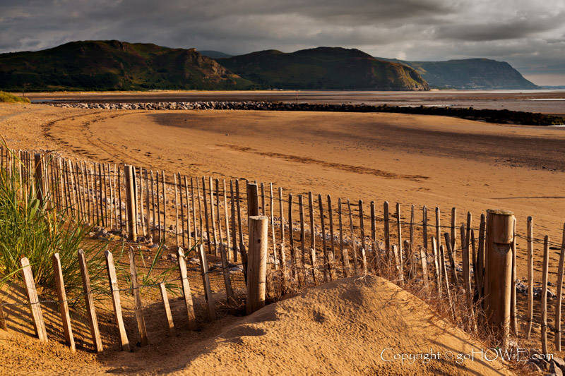 Photo showing wooden fencing partially buried in blown sand on the West Shore, Llandudno, on the North Wales coast