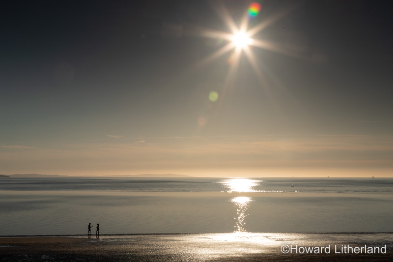 Sun and couple on the West Shore beach, Llandudno, North Wales