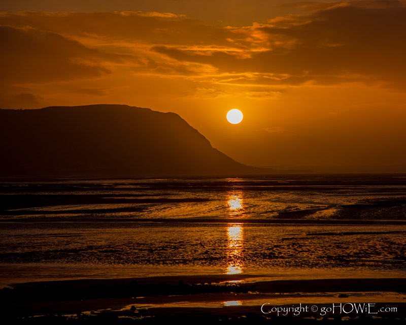 Sunset with clouds adjacent to the headland of Penmaenmawr as viewed from the West Shore at Llandudno on the North Wales coast