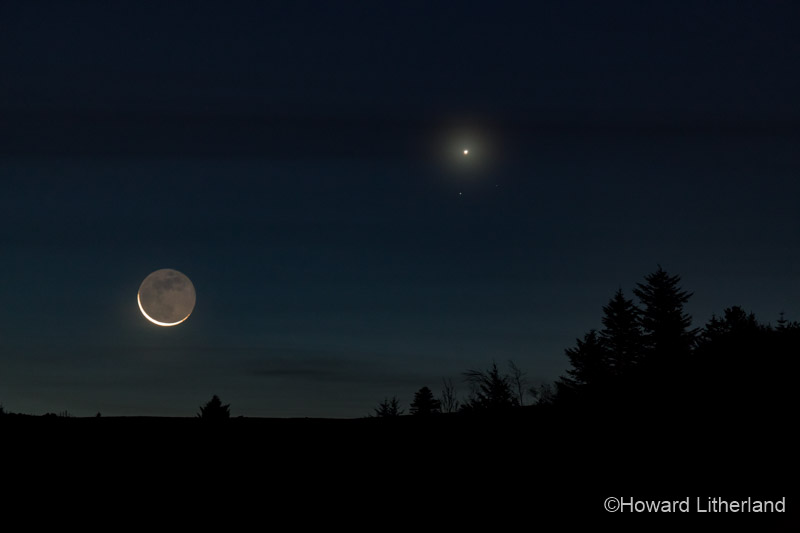 The crescent moon, lit by earthshine, and the planet Venus at dawn over the Clwydian Range Area of Outstanding Natural Beauty in North Wales