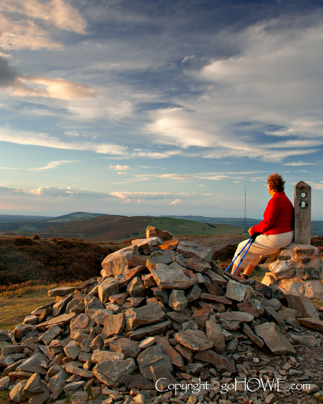 Female hiker resting on a pile of stones at Penycloddiau near Ysceifiog on Offa's Dyke, North Wales