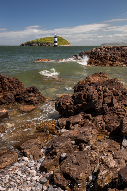 Penmon lighthouse and Puffin Island with a rocky foreshore, Anglesey, North Wales