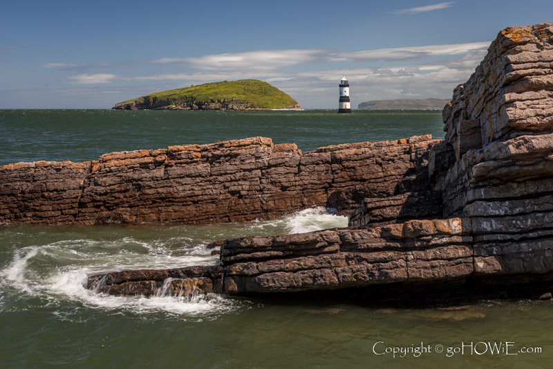 Penmon lighthouse and Puffin Island with a rock shelf, Anglesey, North Wales