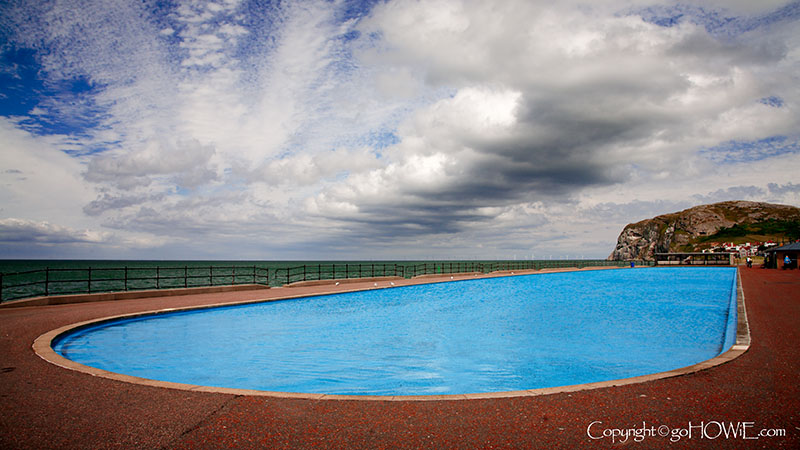 Blue paddling pool on Llandudno promenade with the Little Orme in the background, North Wales coast