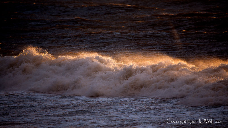 A storm driven wave, touched by sunlight, breaking at the West Shore, Llandudno, North Wales