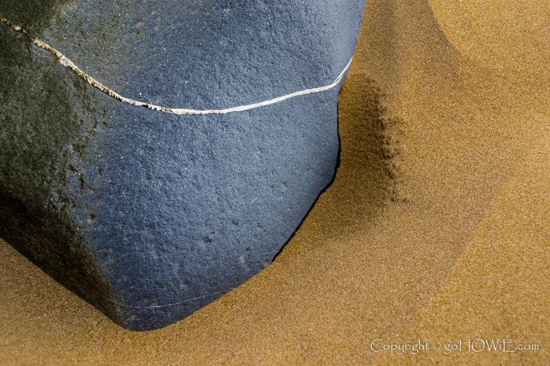Rock with a thin vein of quartz in the sand on the beach at Conway Morfa, North Wales coast