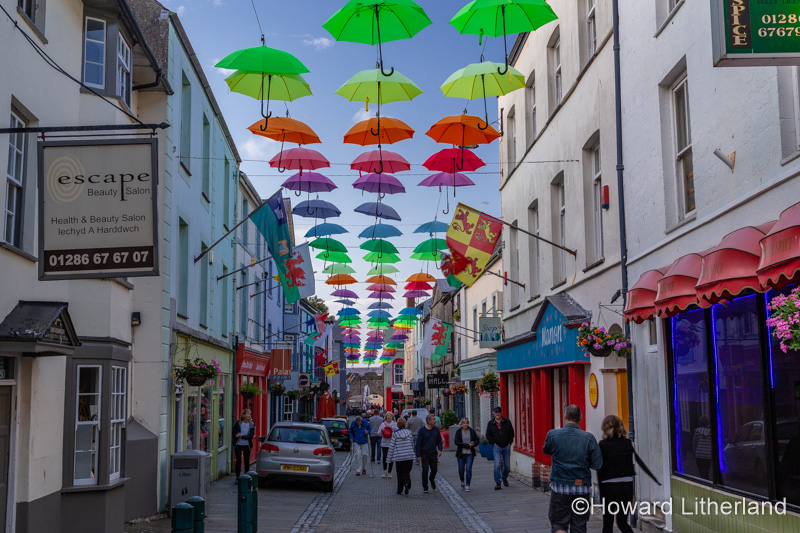 Multi-coloured umbrellas over Palace Street, Caernarfon, North Wales