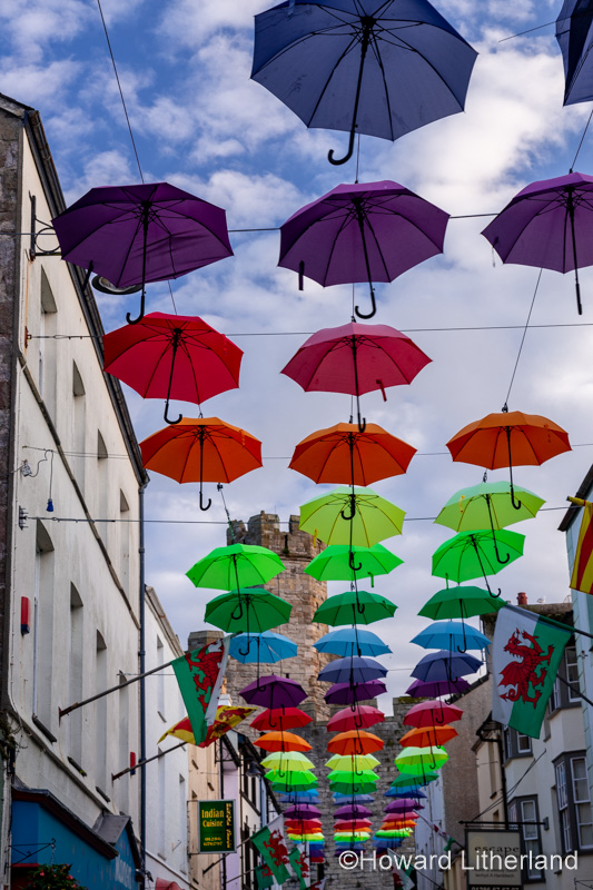 Multi-coloured umbrellas over Palace Street, Caernarfon, North Wales