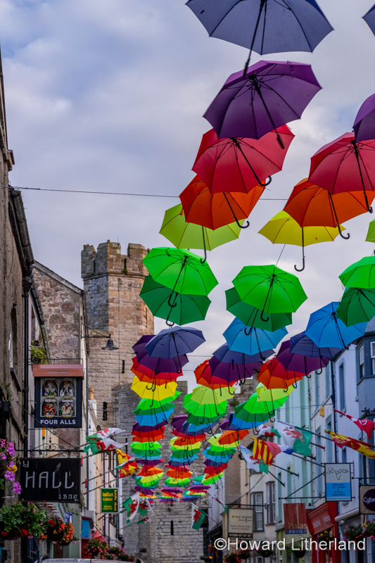Multi-coloured umbrellas over Palace Street, Caernarfon, North Wales