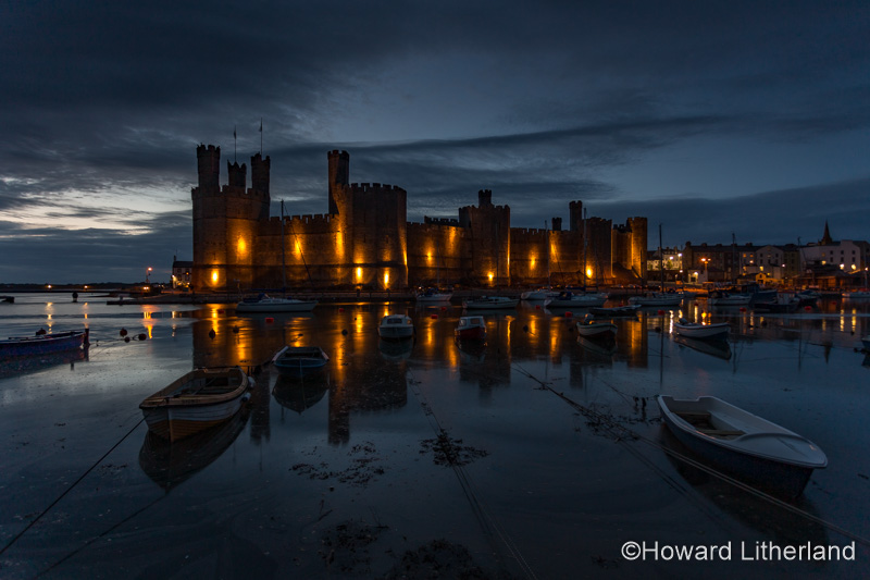 Caernarfon Castle with reflections at dusk on the North Wales coast