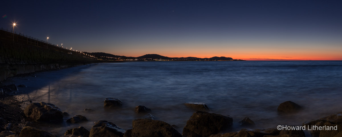 Panoramic image of Colwyn Bay at night at high tide on the North Wales coast