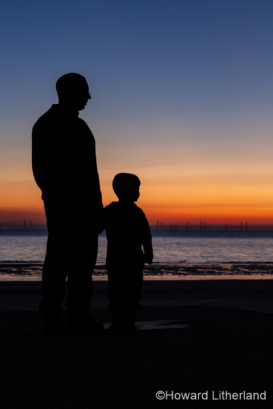 Sculptures of families on the seafront at Colwyn Bay at dawn, North Wales