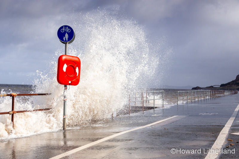 Lifebuoy on Colwyn Bay promenade with crashing waves in a storm on the North Wales coast