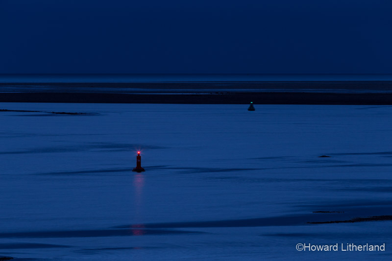 Two marker buoys in the Conwy estuary at night at low tide on the North Wales coast
