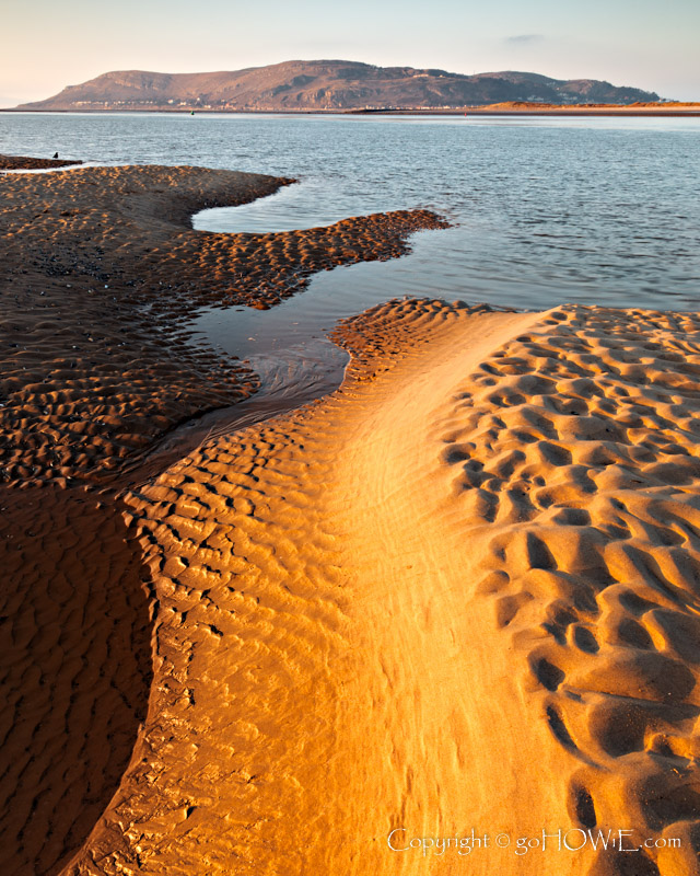 The beach at Conwy Morfa on the North Wales coast at low tide showing contours and patterns in the sand and with the Great Orme headland in the background