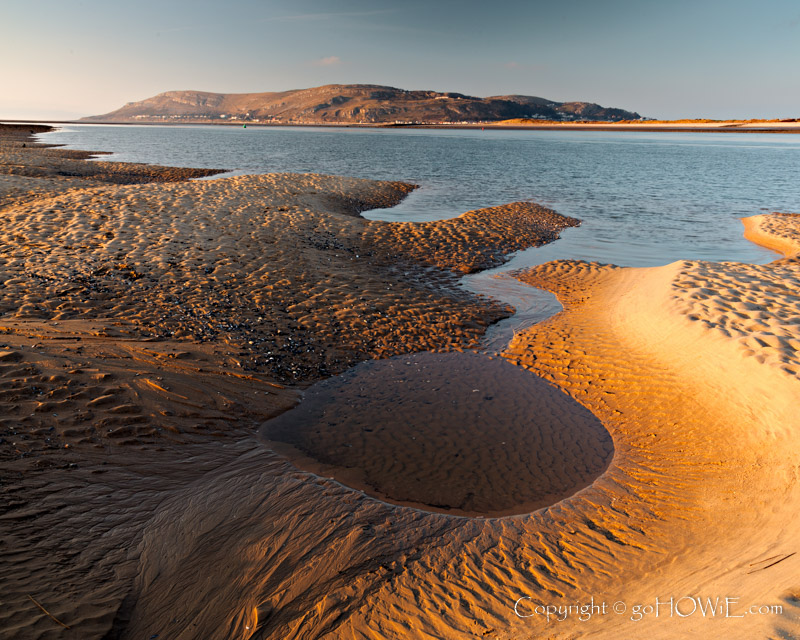 The beach at Conwy Morfa on the North Wales coast at low tide showing contours and patterns in the sand and with the Great Orme headland in the background