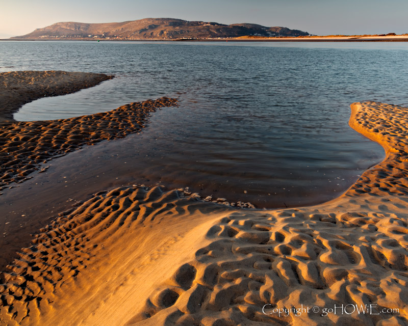The beach at Conwy Morfa on the North Wales coast at low tide showing contours and patterns in the sand and with the Great Orme headland in the background