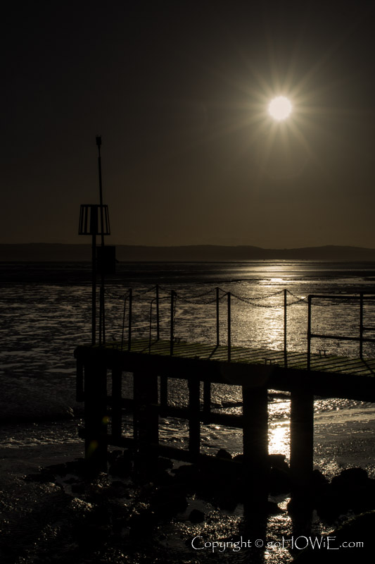 Jetty in silhouette against the sun, West Kirby Marine lake