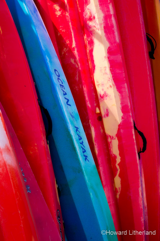 Colourful kayaks, stacked on the beach at Llangrannog on the Ceredigion coast, Mid Wales