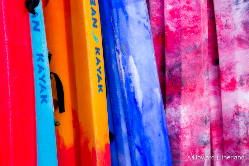 Colourful kayaks, stacked on the beach at Llangrannog on the Ceredigion coast, Mid Wales