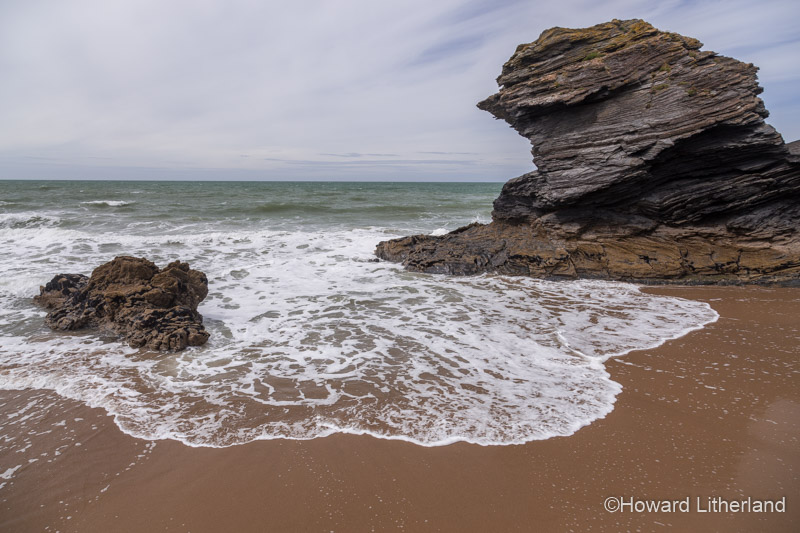 Breaking wave with rocks and sand on the beach at Llangrannog on the Ceredigion coast, Mid Wales