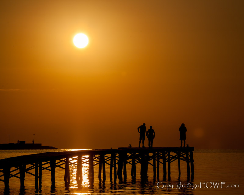 Holiday makers on a jetty at sunrise, Alcudia Bay, Mallorca