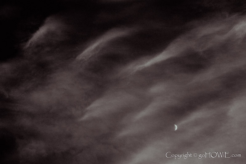Crescent moon behind wispy cirrus clouds