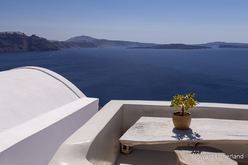 White painted roof terrace with small lemon bush overlooking the Aegean sea at Oia on the island of Santorini