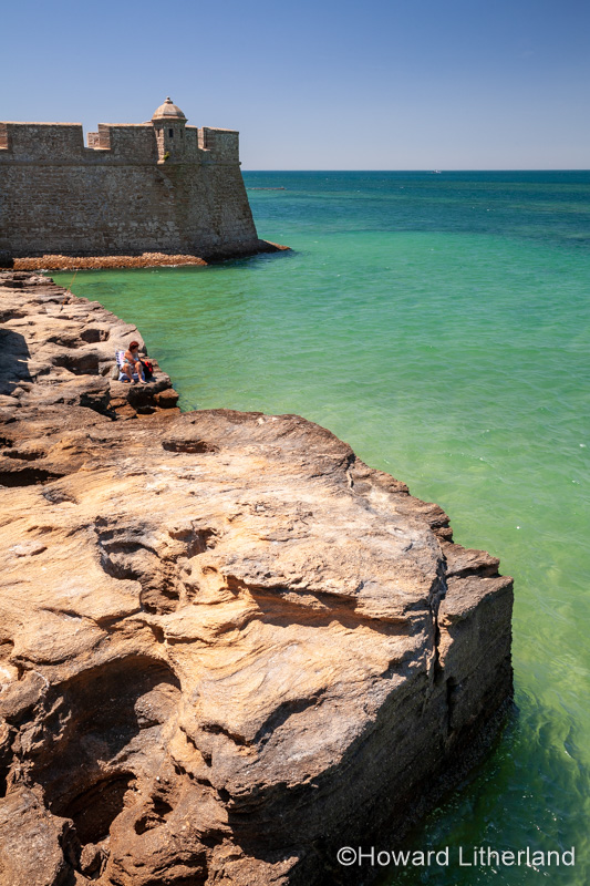 Tourist on rocks by the sea at Cadiz, Spain