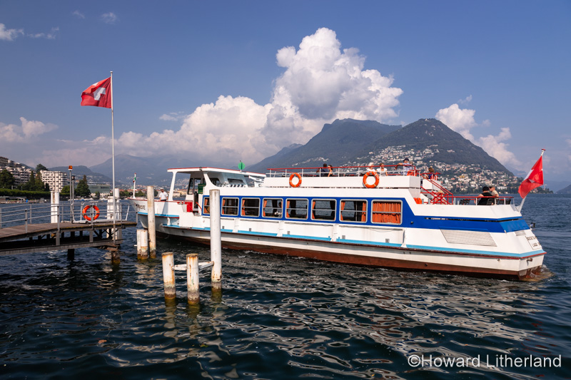 Ferryboat and jetty on the shore of Lake Lugano at Lugano in Switzerland