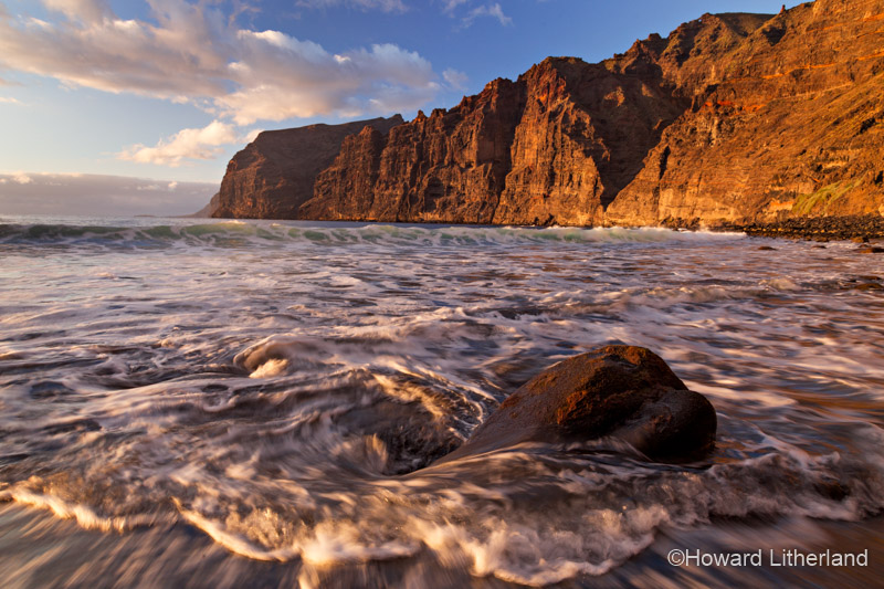 A boulder washed by a receding wave below the sea cliffs on the beach at Los Gigantes on Tenerife in the Canary Islands