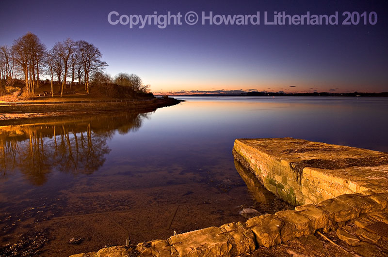 Harbour wall, sea and trees, Caernarfon, North Wales