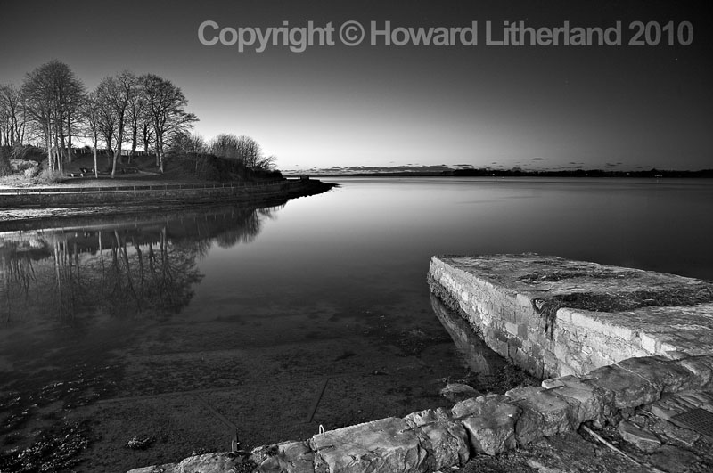 Harbour wall, sea and trees, Caernarfon, North Wales
